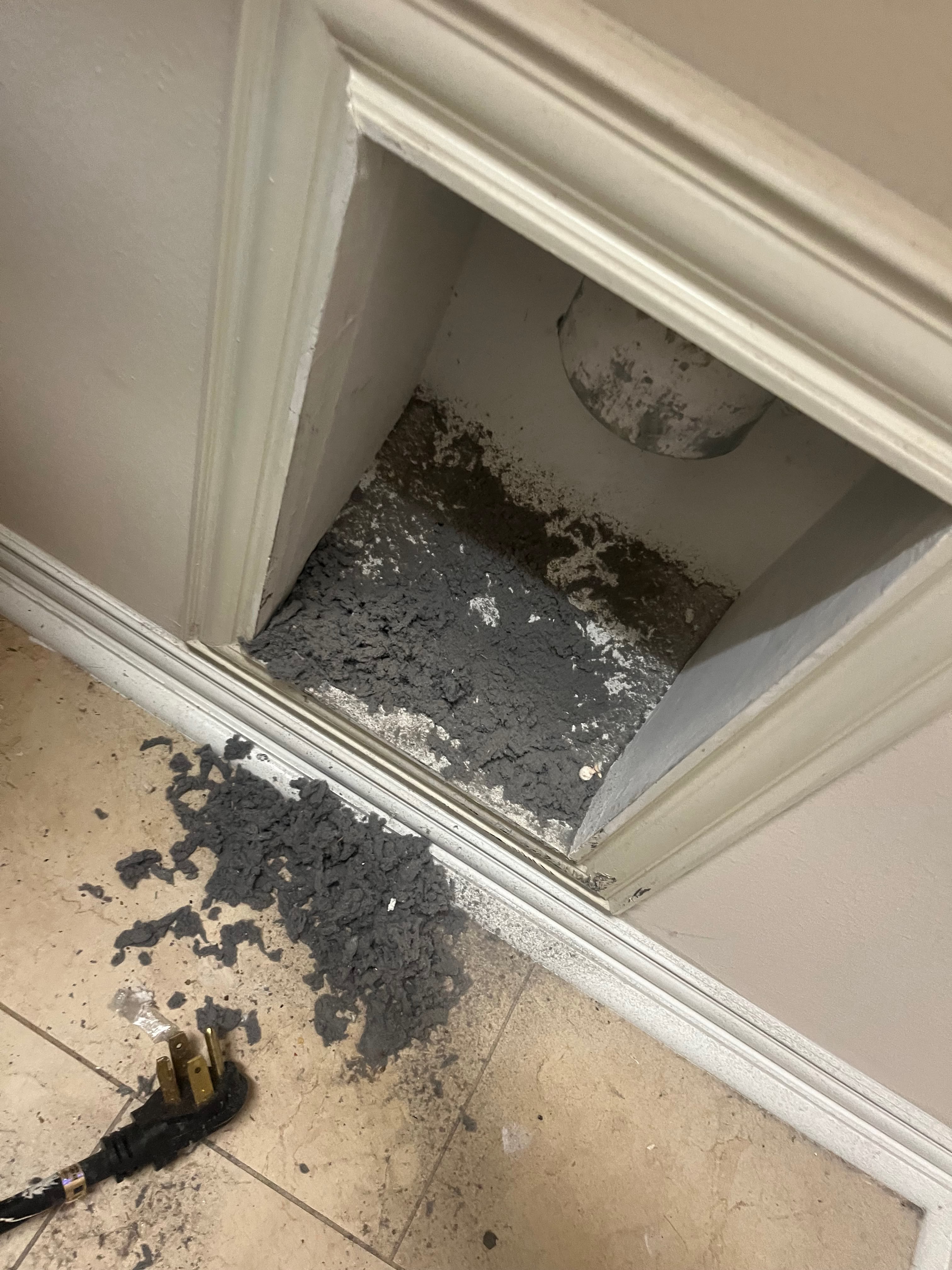 Dryer vent packed with lint spilling onto the floor in a Preston Hollow Dallas home before cleaning