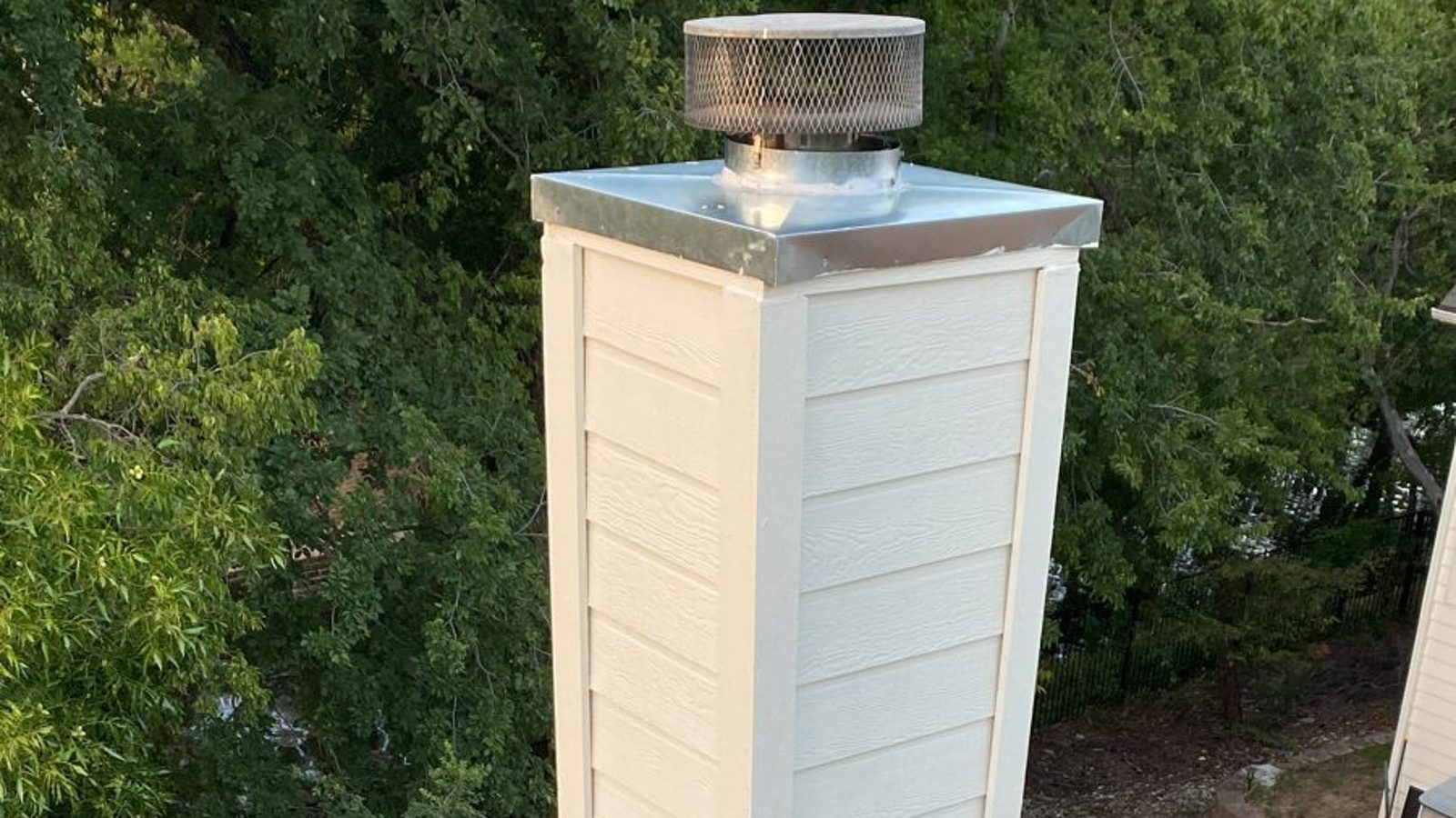Rooftop chimney with a new stainless cap after a chimney sweep in Dallas TX